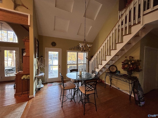 dining area with wood-type flooring, a notable chandelier, and high vaulted ceiling