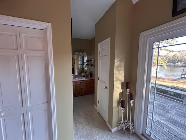 corridor with sink and light carpet