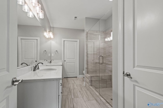 bathroom with a stall shower, double vanity, and baseboards