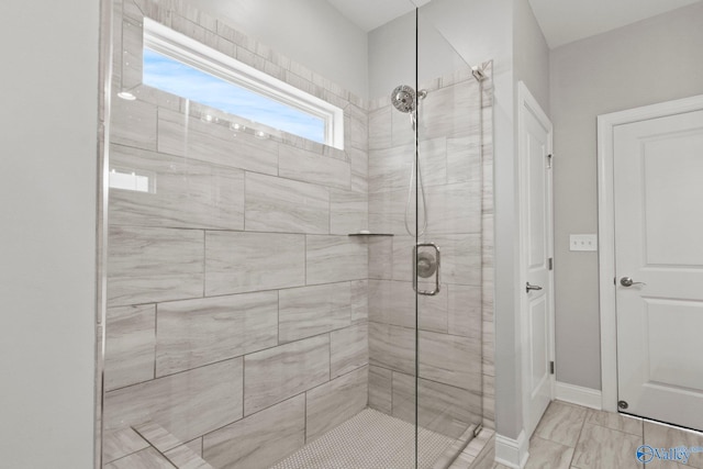 bathroom with a shower stall and baseboards