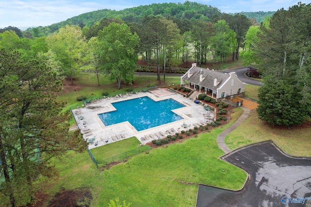 community pool with a patio area and a wooded view