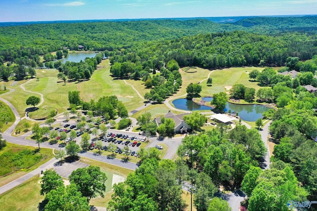 bird's eye view of a heavily wooded area, a nearby body of water, and a local golf course