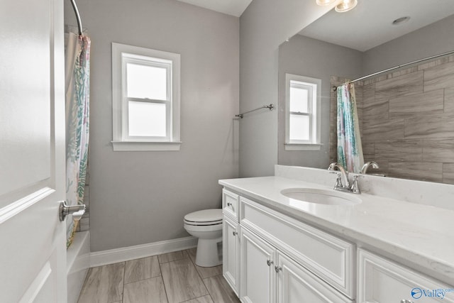 full bath with plenty of natural light, toilet, baseboards, and vanity