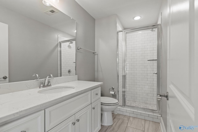 full bathroom featuring a stall shower, toilet, vanity, and recessed lighting