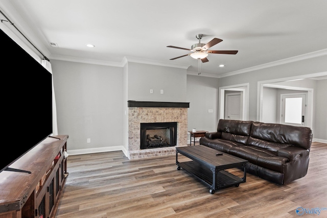 living room featuring ceiling fan, light wood-type flooring, baseboards, a brick fireplace, and recessed lighting