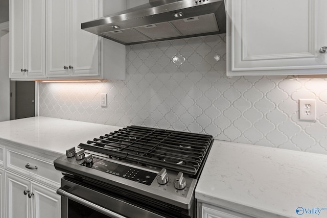 kitchen featuring gas range, exhaust hood, white cabinets, backsplash, and light stone countertops