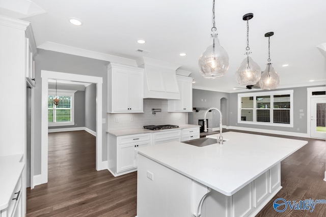 kitchen featuring white cabinetry, sink, tasteful backsplash, and a large island with sink