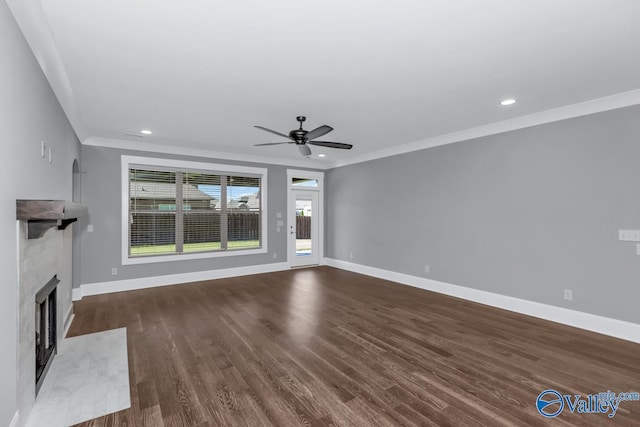 unfurnished living room featuring dark wood-type flooring, ceiling fan, crown molding, and a tile fireplace