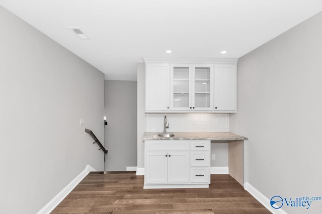 bar featuring white cabinetry, sink, decorative backsplash, and light stone countertops