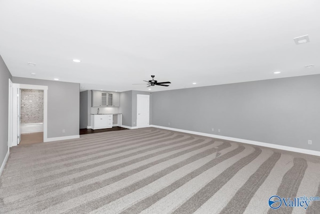 unfurnished living room with sink, ceiling fan, and carpet