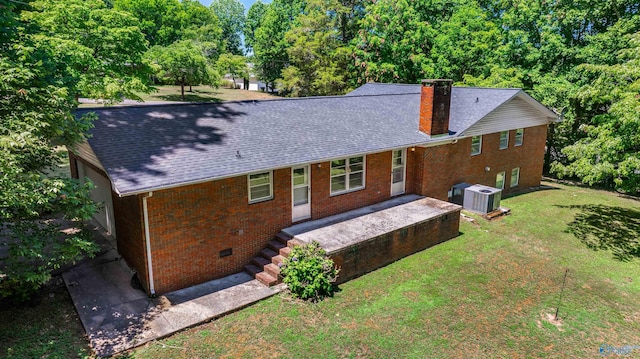 rear view of house with central AC unit and a lawn