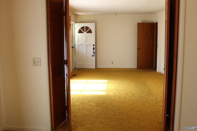 corridor featuring light carpet and a textured ceiling