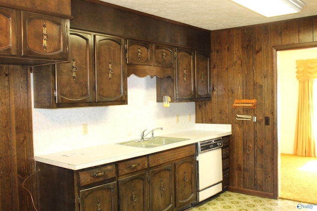 kitchen featuring wood walls, dark brown cabinets, sink, and white dishwasher