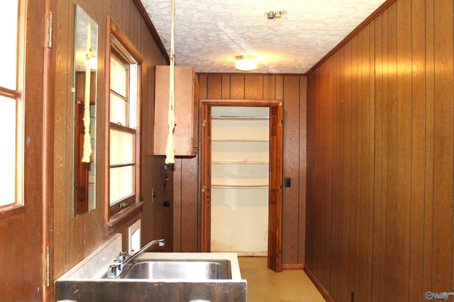 kitchen with sink, wooden walls, and a textured ceiling