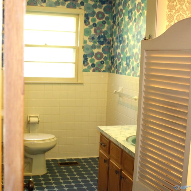 bathroom with vanity, tile walls, and toilet