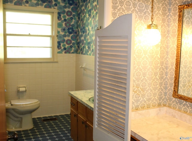 bathroom featuring tile walls, vanity, and toilet