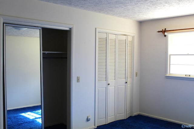 unfurnished bedroom with a textured ceiling, a closet, and dark colored carpet