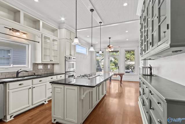 kitchen featuring sink, a kitchen island, decorative light fixtures, a kitchen breakfast bar, and dark hardwood / wood-style flooring