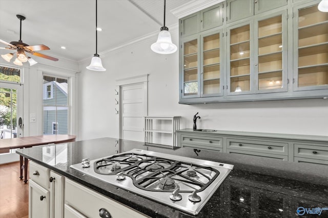 kitchen with pendant lighting, hardwood / wood-style flooring, dark stone countertops, crown molding, and white gas stovetop