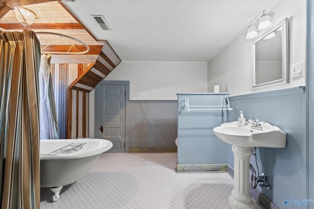 bathroom featuring crown molding, wood walls, and a bath