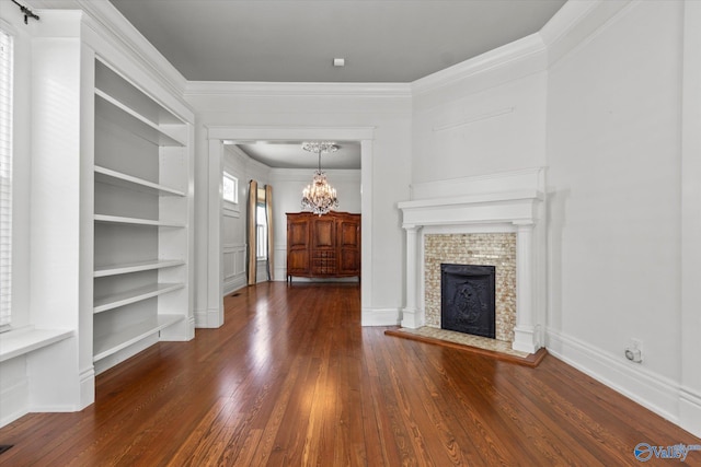 unfurnished living room featuring an inviting chandelier, ornamental molding, dark hardwood / wood-style floors, and built in features