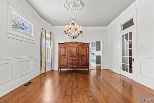 foyer entrance featuring ornamental molding, wood-type flooring, and a chandelier