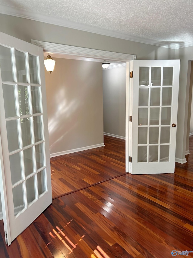 spare room featuring dark wood-type flooring, crown molding, and a textured ceiling