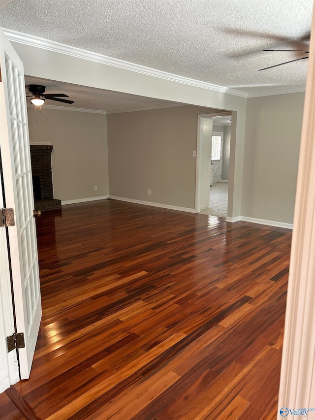 spare room with dark hardwood / wood-style flooring, a textured ceiling, a fireplace, and ceiling fan