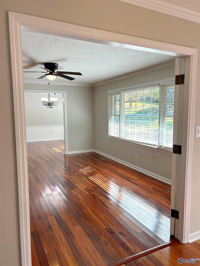 unfurnished room featuring ornamental molding, dark wood-type flooring, ceiling fan with notable chandelier, and a textured ceiling