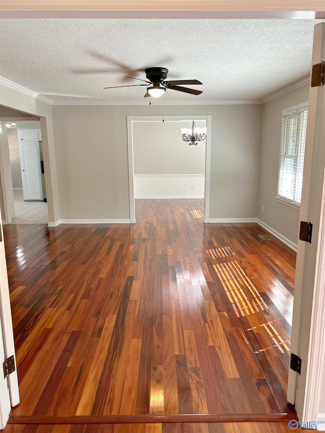 empty room featuring crown molding, dark hardwood / wood-style floors, ceiling fan with notable chandelier, and a textured ceiling