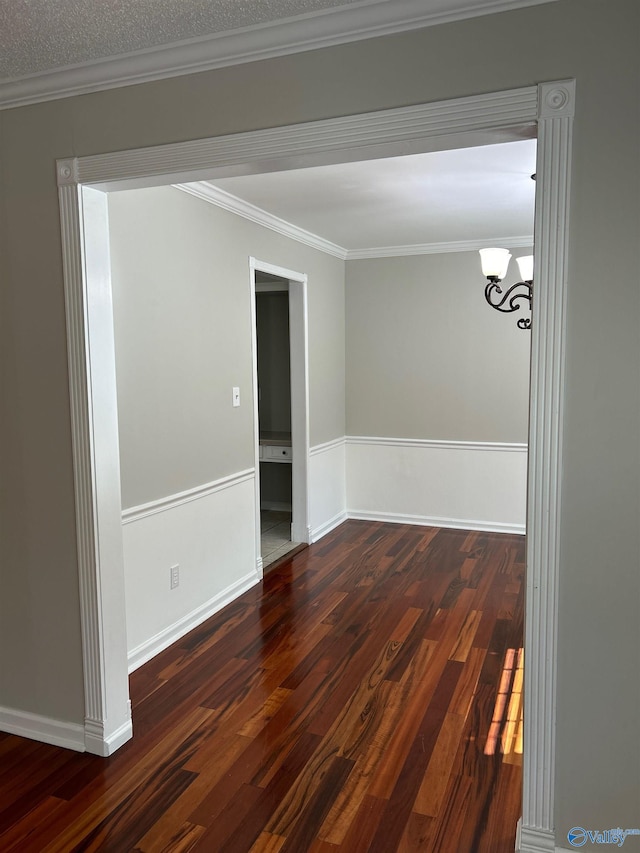 empty room featuring a notable chandelier, crown molding, dark wood-type flooring, and a textured ceiling