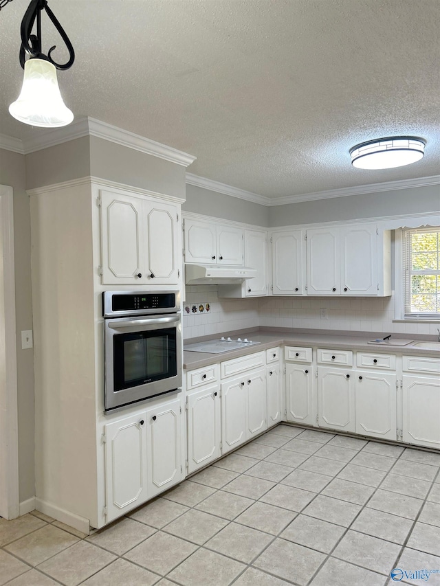 kitchen with hanging light fixtures, white cabinetry, oven, and backsplash