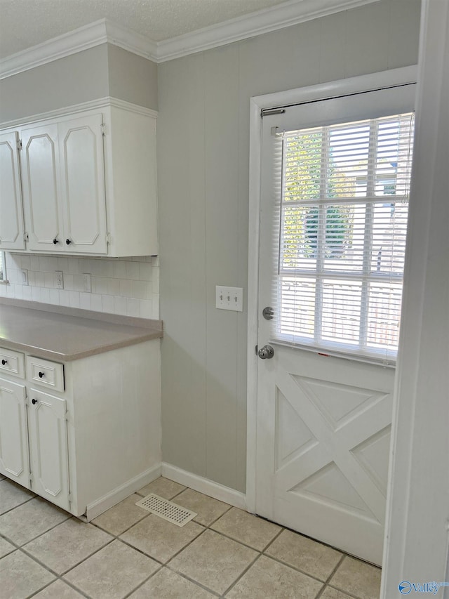 doorway featuring crown molding and light tile patterned floors