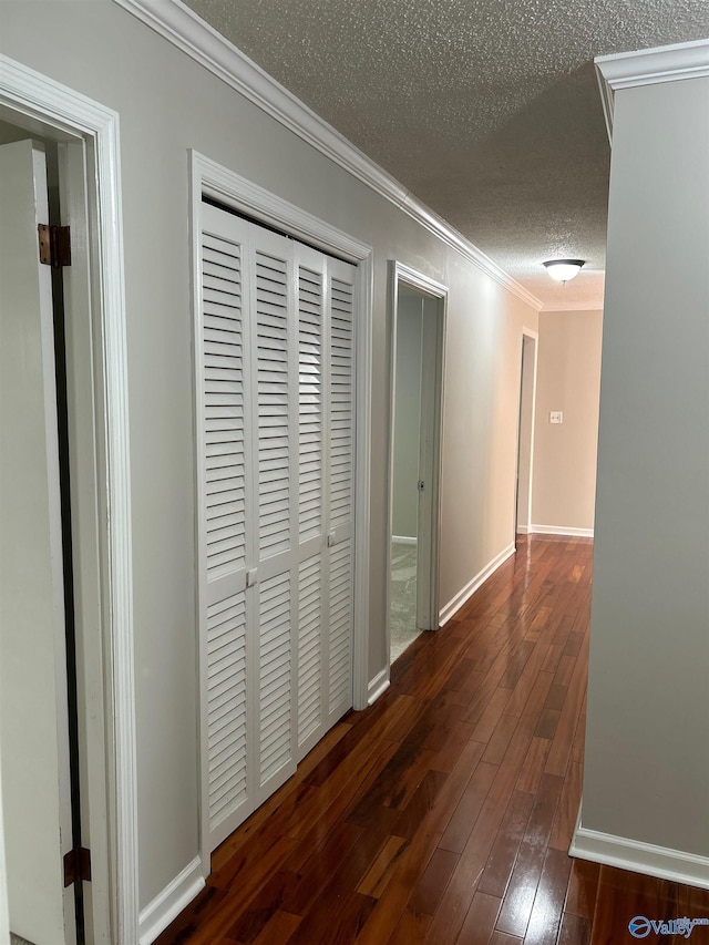 hall with dark wood-type flooring, ornamental molding, and a textured ceiling