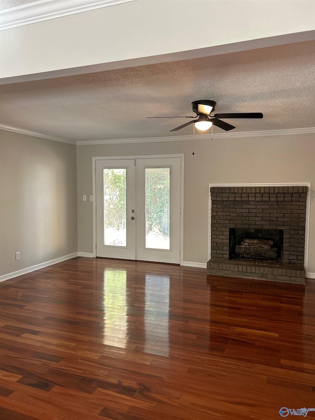 unfurnished living room featuring dark wood-type flooring, a textured ceiling, ornamental molding, ceiling fan, and a fireplace