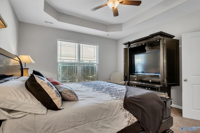 carpeted bedroom featuring ceiling fan and a raised ceiling