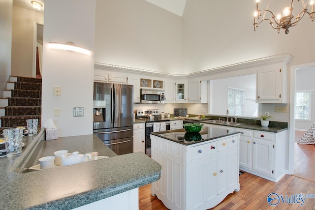 kitchen featuring white cabinets, stainless steel appliances, a towering ceiling, and sink