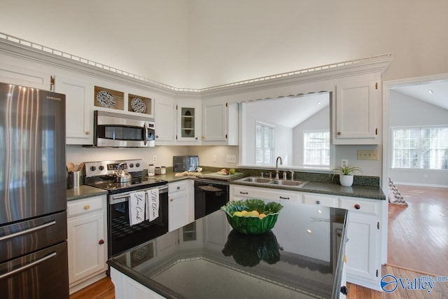 kitchen featuring lofted ceiling, white cabinetry, stainless steel appliances, light hardwood / wood-style floors, and sink