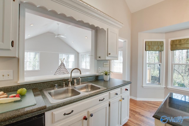 kitchen with sink, white cabinets, black dishwasher, and vaulted ceiling