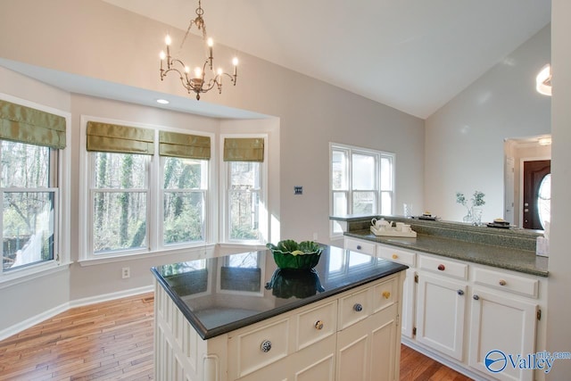 kitchen with white cabinets, a center island, light hardwood / wood-style floors, and lofted ceiling