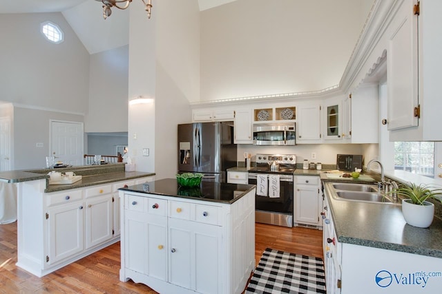 kitchen with white cabinets, stainless steel appliances, a center island, and sink