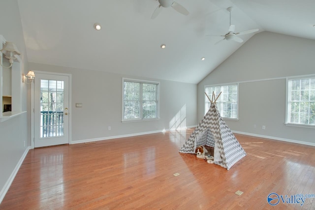 unfurnished living room with ceiling fan, vaulted ceiling, and light wood-type flooring