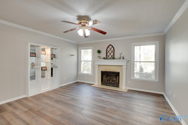 unfurnished living room featuring a textured ceiling, a healthy amount of sunlight, light hardwood / wood-style flooring, and ornamental molding