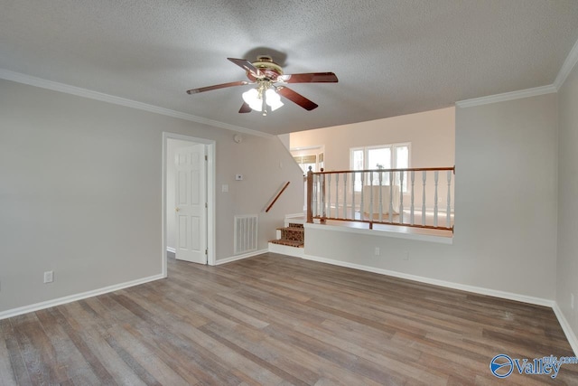 empty room featuring ceiling fan, hardwood / wood-style floors, a textured ceiling, and crown molding