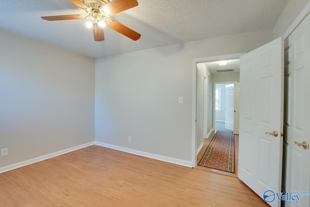 spare room featuring a textured ceiling, light hardwood / wood-style flooring, and ceiling fan