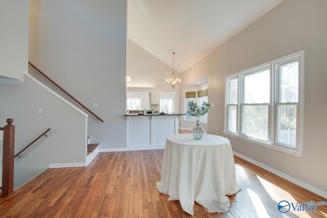 dining area with a chandelier, high vaulted ceiling, and light hardwood / wood-style floors