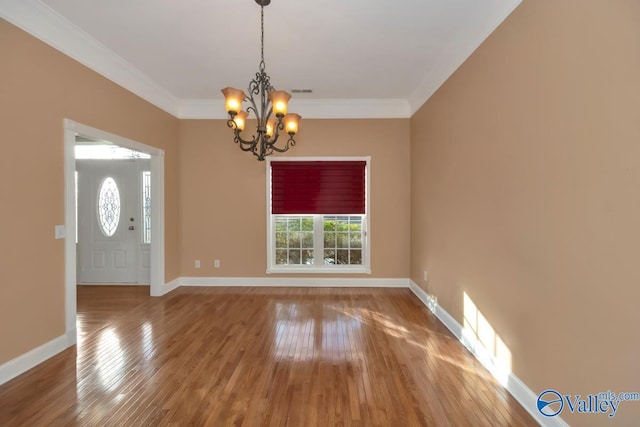 foyer entrance with hardwood / wood-style floors, a notable chandelier, and ornamental molding