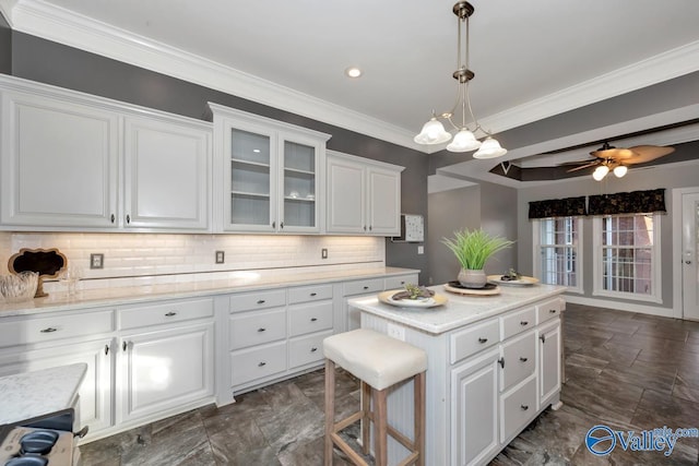 kitchen with hanging light fixtures, a center island, white cabinetry, and ceiling fan