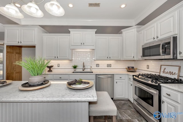 kitchen with sink, stainless steel appliances, decorative light fixtures, white cabinets, and ornamental molding