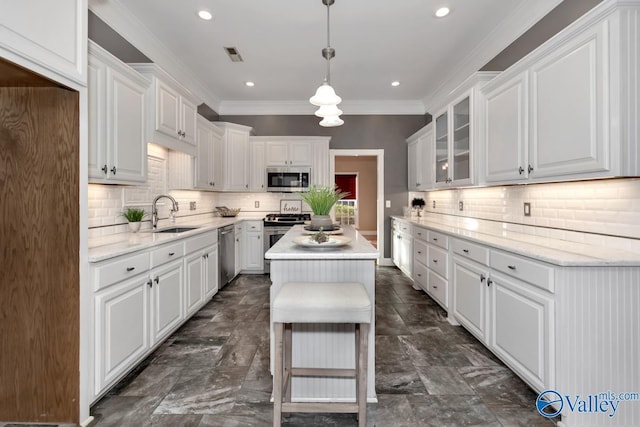 kitchen with appliances with stainless steel finishes, sink, decorative light fixtures, white cabinets, and a kitchen island